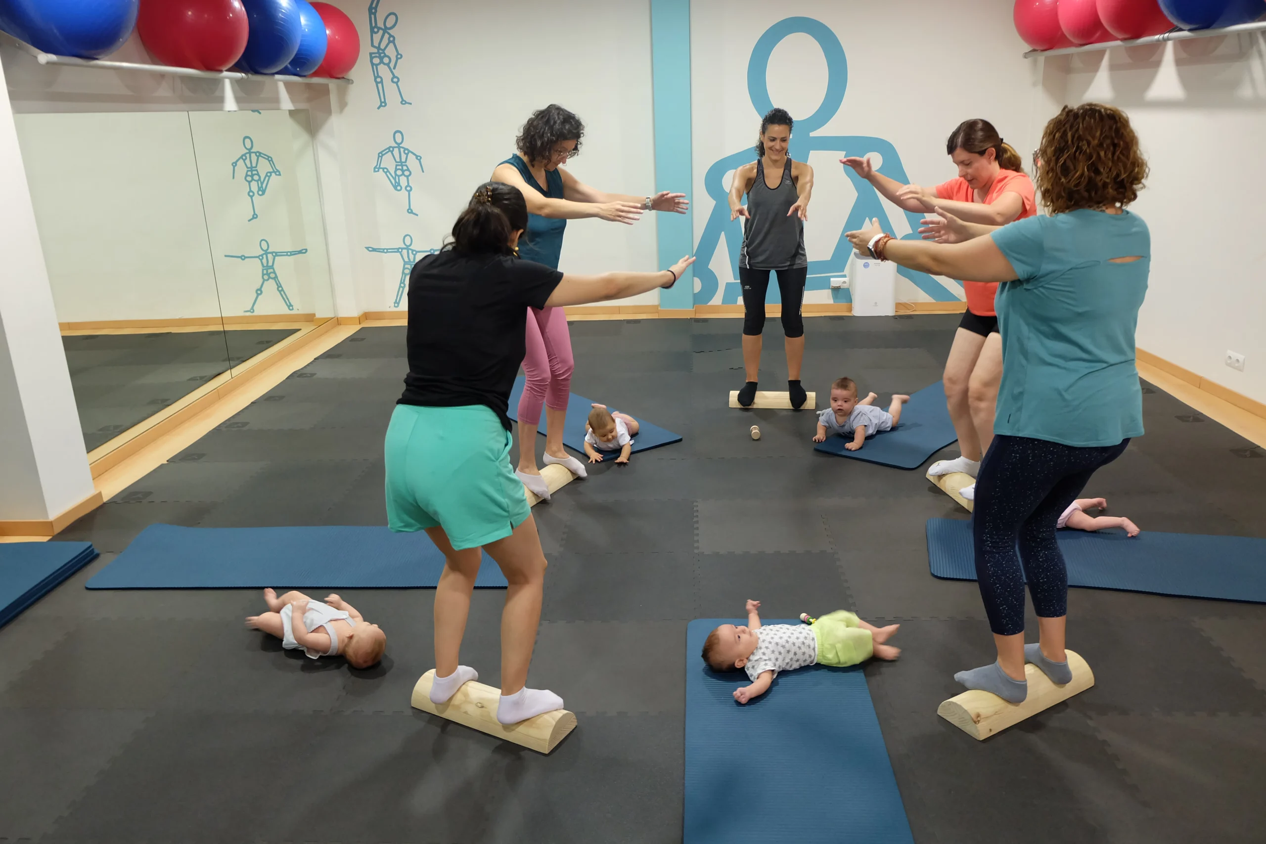 Grupo de madres de Carlet con sus bebés haciendo equilibrio en clase de Recuperación Posparto.