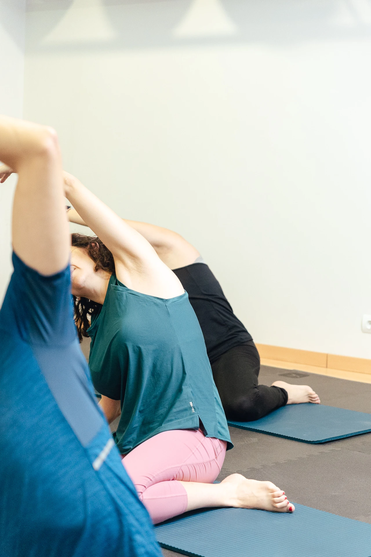 Personas de Carlet en clase de Pilates Terapeutico realizando estiramientos de espalda en colchonetas.