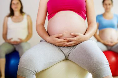 Tres mujeres embarazadas sentadas en pelota de Pilates haciendo ejercicio