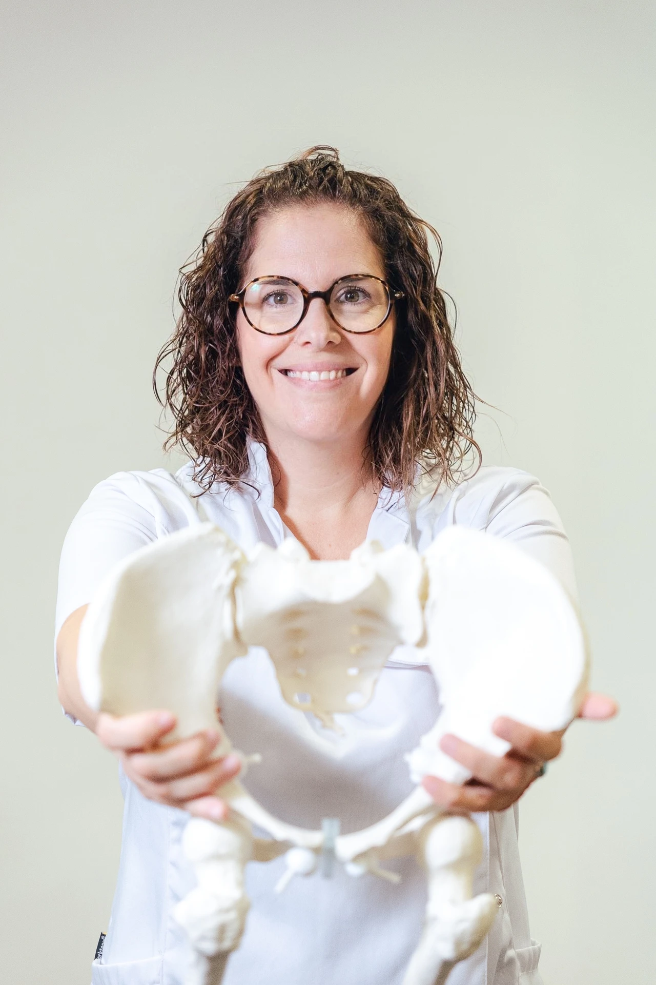 Estel Roig, Experta en Suelo Pelvico, sosteniendo una pelvis fisiológica con ambas manos.