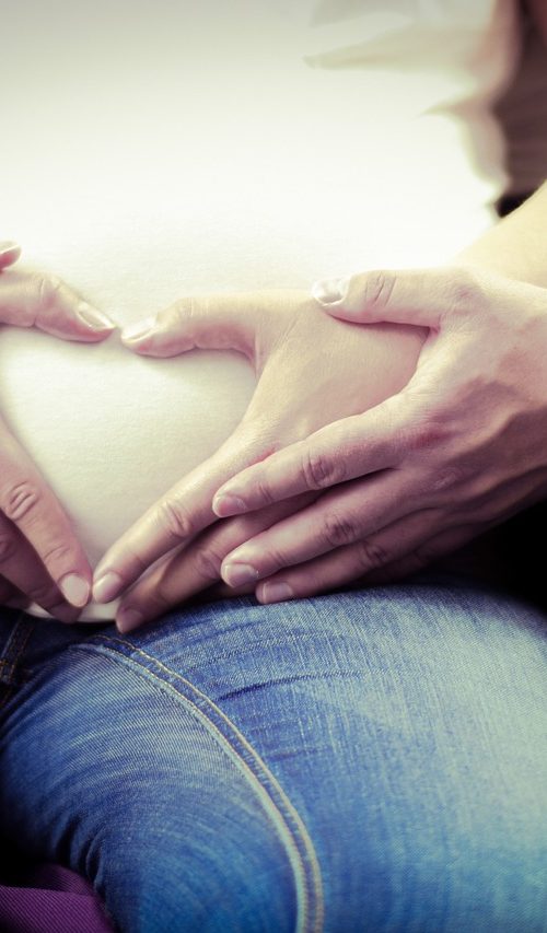 Pareja disfrutando del embarazo y preparándose para realizar un masaje perineal.